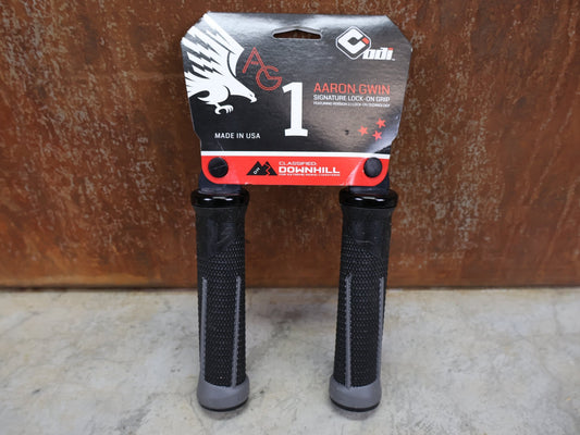 Griffe und Lenkerbänder von Odi, ODI AG - 1 LOCK - ON 2.1 MTB GRIFFE – 135 MM / BLACK - GRAPHITE – AARON GWIN SIGNATURE vor USEDBIKES - OB.DE Hintergrund