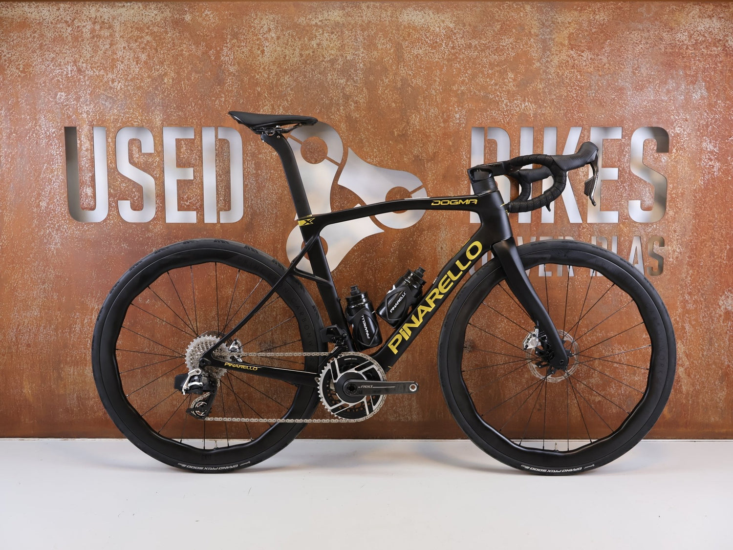 Rennrad von Pinarello, PINARELLO DOGMA X DISC RED AXS PRICETON GRIT 4540 / 53CM GOLD vor USEDBIKES-OB.DE Hintergrund