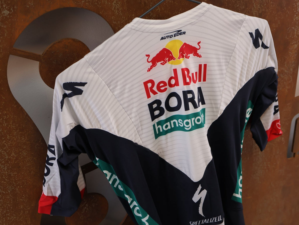 Anzug - BOH von Specialized, Red Bull BORA hansgrohe Aero Skinsuit Kurzarm Specialized vor USEDBIKES-OB.DE Hintergrund