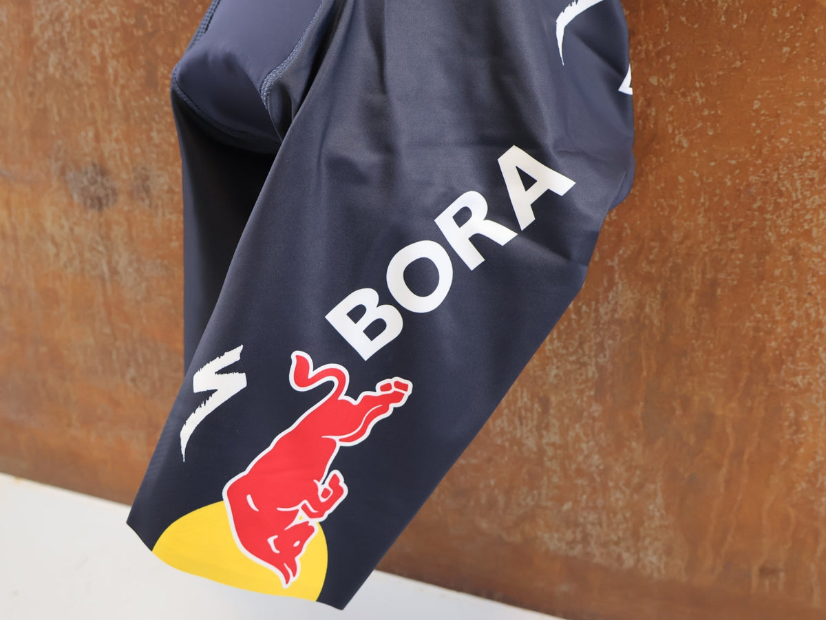 Anzug - BOH von Specialized, Red Bull BORA hansgrohe Aero Skinsuit Kurzarm Specialized vor USEDBIKES-OB.DE Hintergrund