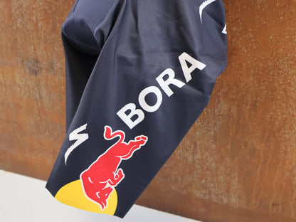 Anzug - BOH von Specialized, Red Bull BORA hansgrohe Aero Skinsuit Kurzarm Specialized vor USEDBIKES-OB.DE Hintergrund