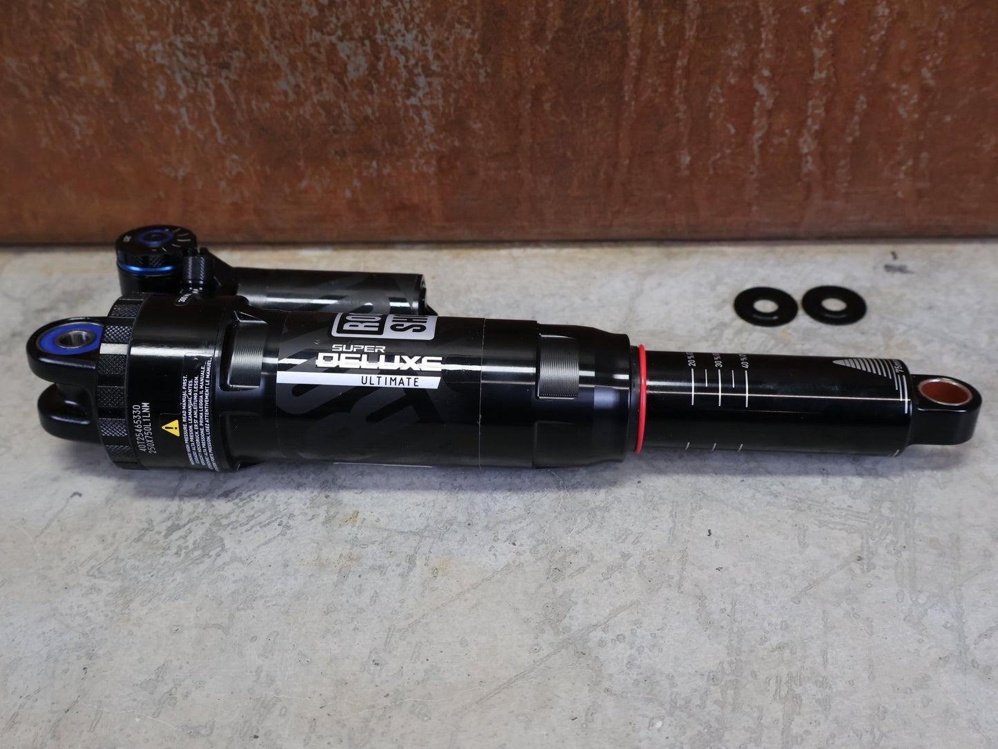 Federgabel & Dämpfer von Rock Shox, ROCKSHOX SUPER DELUXE ULTIMATE DH DÄMPFER 250X75 MM – DEBONAIR vor USEDBIKES - OB.DE Hintergrund