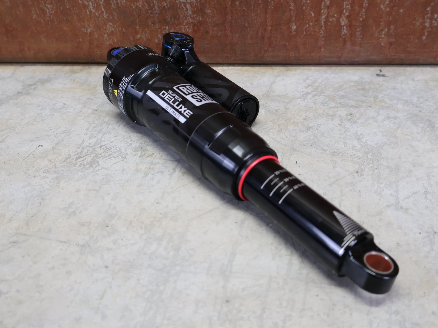 Federgabel & Dämpfer von Rock Shox, ROCKSHOX SUPER DELUXE ULTIMATE DH DÄMPFER 250X75 MM – DEBONAIR vor USEDBIKES - OB.DE Hintergrund