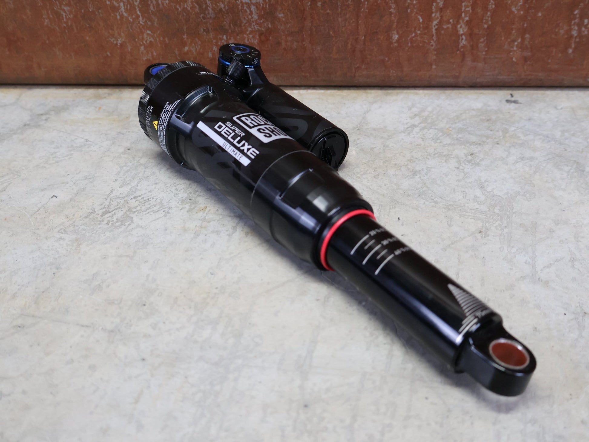 Federgabel & Dämpfer von Rock Shox, ROCKSHOX SUPER DELUXE ULTIMATE DH DÄMPFER 250X75 MM – DEBONAIR vor USEDBIKES - OB.DE Hintergrund