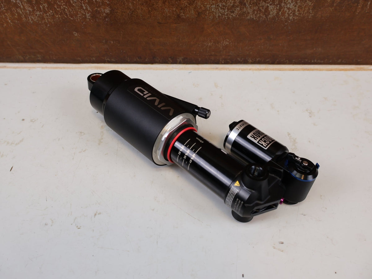 Federgabel & Dämpfer von Rock Shox, RockShox Vivid Ultimate Air Dämpfer 205x65mm Trunnion RC2T vor USEDBIKES-OB.DE Hintergrund
