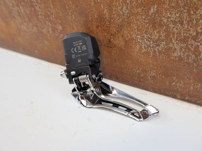 Schaltungsteile von Shimano, SHIMANO 105 DI2 UMWERFER FD-R7150 / 2X12-FACH / ANLÖT / 142 G vor USEDBIKES-OB.DE Hintergrund