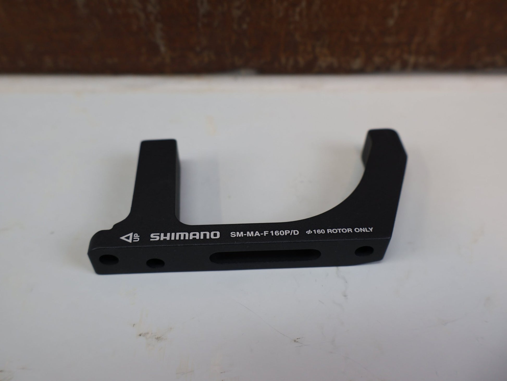 Bremsadapter von Shimano, SHIMANO ADAPTER SM-MA-F160P/D / FLATMOUNT GABEL AUF PM SATTEL / VR 160 MM vor USEDBIKES-OB.DE Hintergrund