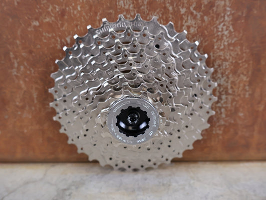 Kassette & Zahnkränze von Shimano, SHIMANO ALIVIO CS - HG400 - 9 KASSETTE / 9 - FACH / 11 - 34 ZÄHNE / HYPERGLIDE / SILVER vor USEDBIKES - OB.DE Hintergrund