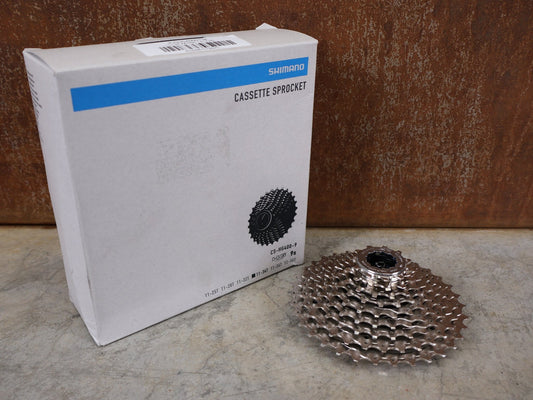 Kassette & Zahnkränze von Shimano, SHIMANO ALIVIO CS - HG400 - 9 KASSETTE / 9 - FACH / 11 - 34 ZÄHNE / HYPERGLIDE / SILVER vor USEDBIKES - OB.DE Hintergrund