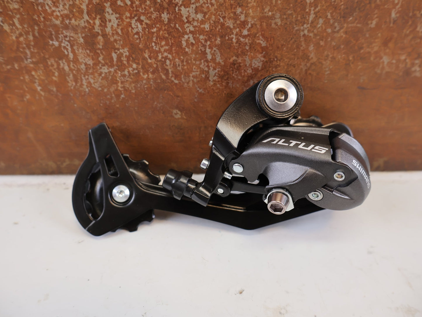 Schaltungsteile von Shimano, SHIMANO ALTUS RD M370 SCHALTWERK 9 FACH MAX 34 T vor USEDBIKES-OB.DE Hintergrund