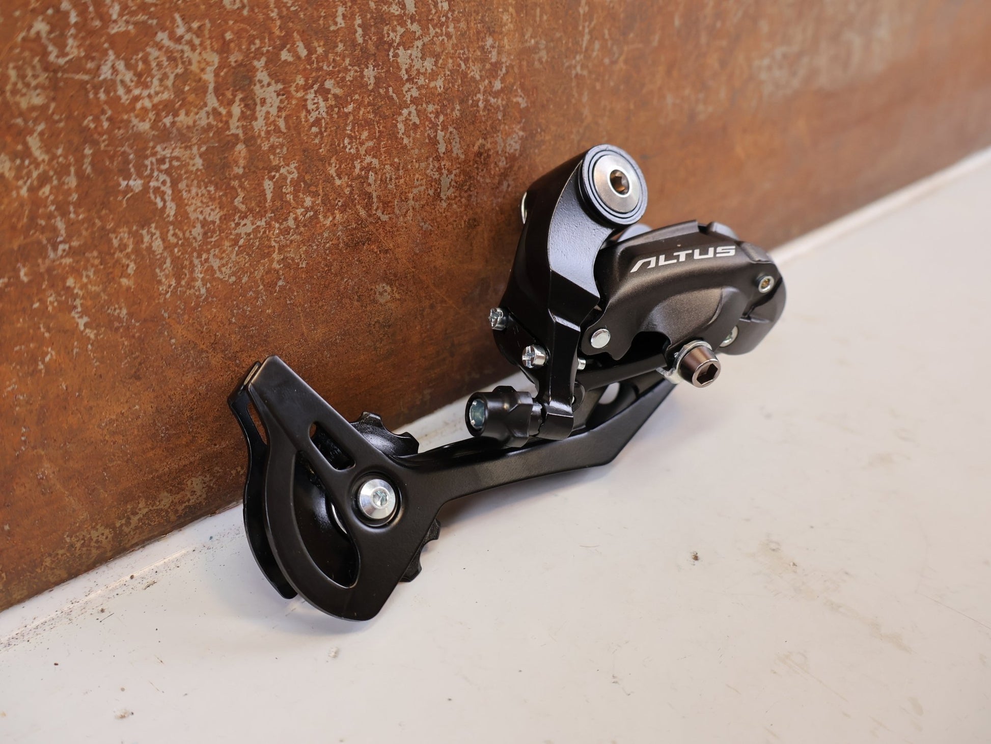 Schaltungsteile von Shimano, SHIMANO ALTUS RD M370 SCHALTWERK 9 FACH MAX 34 T vor USEDBIKES-OB.DE Hintergrund