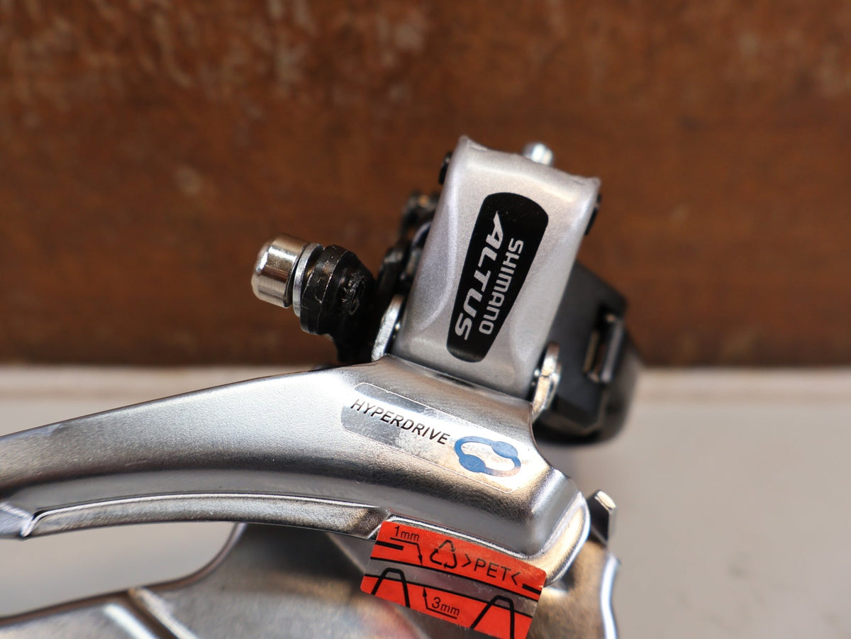 Schaltungsteile von Shimano, SHIMANO ALTUS UMWERFER FD-M313-6 3X7/8-FACH SCHELLE DUAL PULL vor USEDBIKES-OB.DE Hintergrund