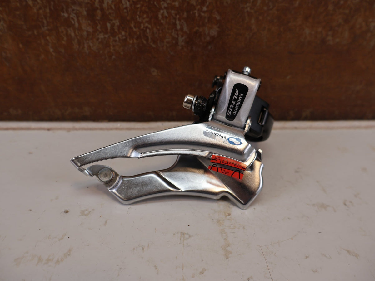 Schaltungsteile von Shimano, SHIMANO ALTUS UMWERFER FD-M313-6 3X7/8-FACH SCHELLE DUAL PULL vor USEDBIKES-OB.DE Hintergrund