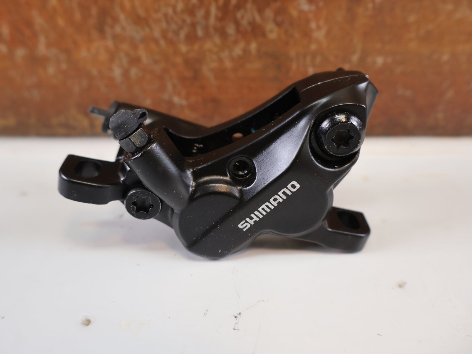 Bremse von Shimano, SHIMANO BR - MT520 BREMSSATTEL / 4 - KOLBEN / POSTMOUNT / KERAMIK - KOLBEN / EBRMT520MPRXL vor USEDBIKES - OB.DE Hintergrund