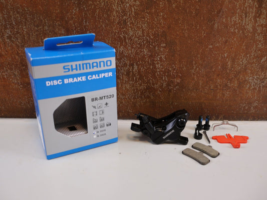 Bremse von Shimano, SHIMANO BR - MT520 BREMSSATTEL / 4 - KOLBEN / POSTMOUNT / KERAMIK - KOLBEN / EBRMT520MPRXL vor USEDBIKES - OB.DE Hintergrund