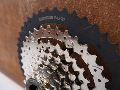 Kassette & Zahnkränze von Shimano, SHIMANO CS-HG400-8 KASSETTE / 8-FACH 11-40 ZÄHNE MEGA RANGE HYPERGLIDE MTB vor USEDBIKES-OB.DE Hintergrund