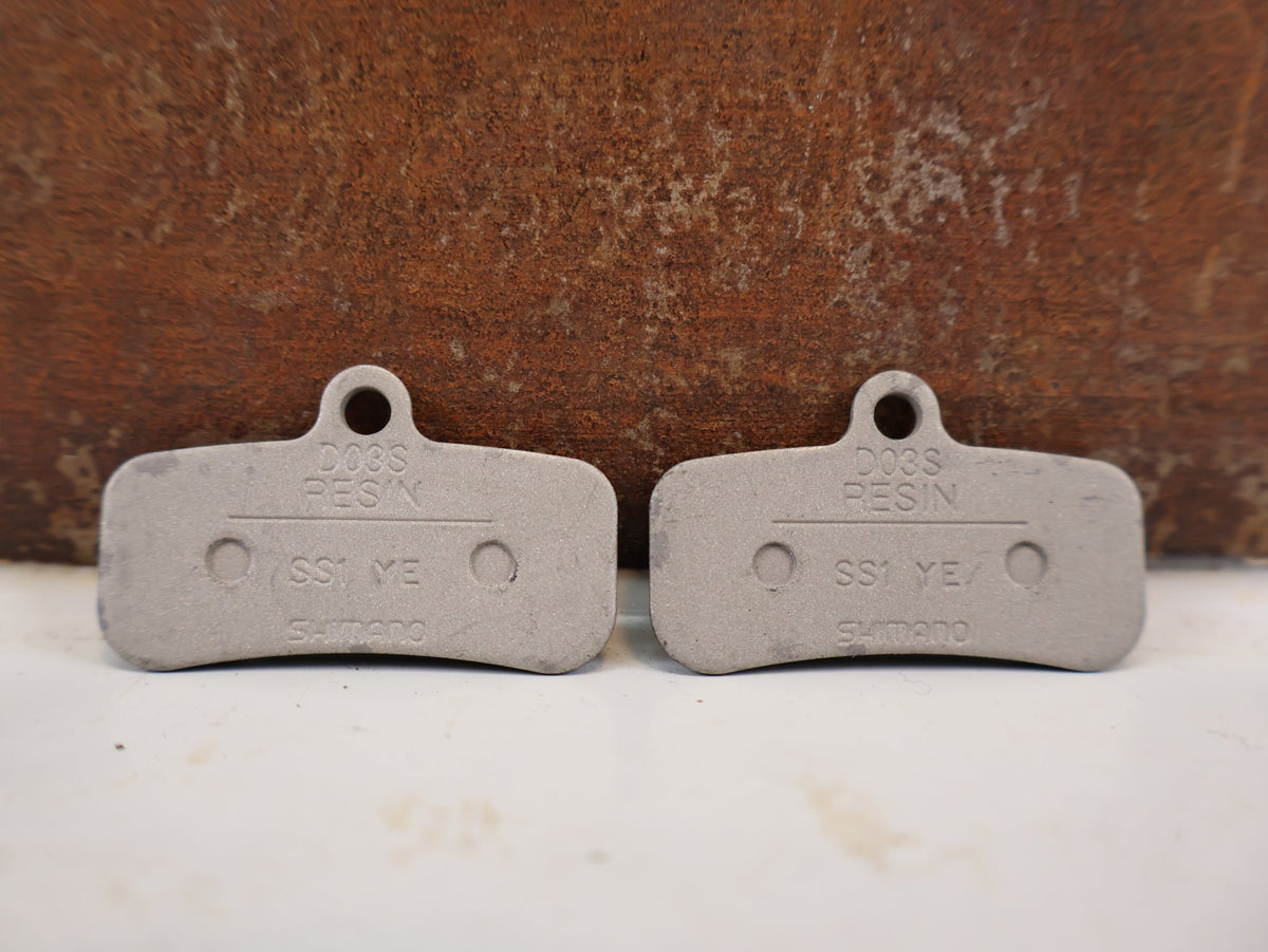 Bremsbelag von Shimano, Shimano D03S Resin Bremsbeläge 4-Kolben XT SLX EBP D03SRXA vor USEDBIKES-OB.DE Hintergrund