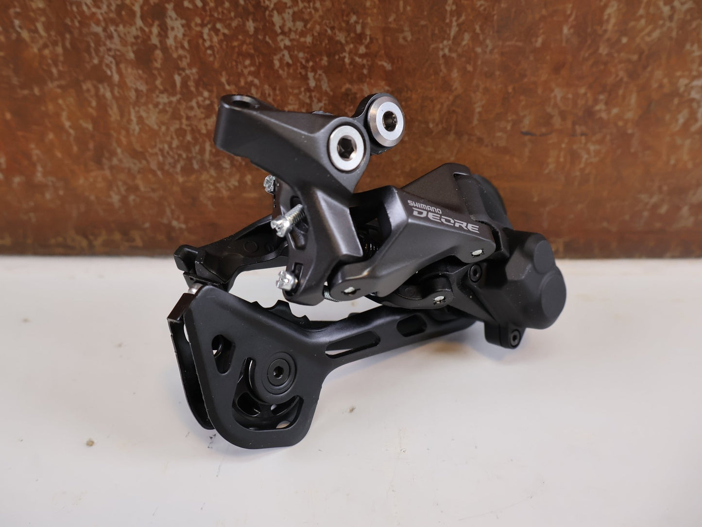Schaltungsteile von Shimano, SHIMANO DEORE RD - M5120 SCHALTWERK / 10/11 - FACH / SHADOW RD+ / SGS LANG / 4550170618544 vor USEDBIKES - OB.DE Hintergrund