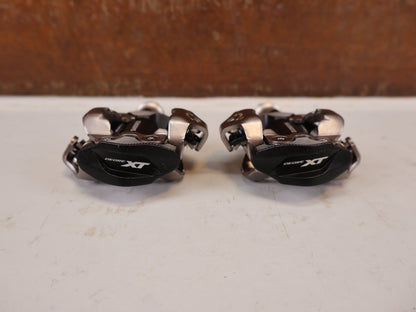 Pedale von Shimano, Shimano Deore XT PD-M8100 SPD Pedale Klickpedale 342g vor USEDBIKES-OB.DE Hintergrund