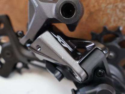 Schaltungsteile von Shimano, SHIMANO DEORE XT RD-M8120 / SCHALTWERK / 2X12-FACH / LONG CAGE vor USEDBIKES-OB.DE Hintergrund