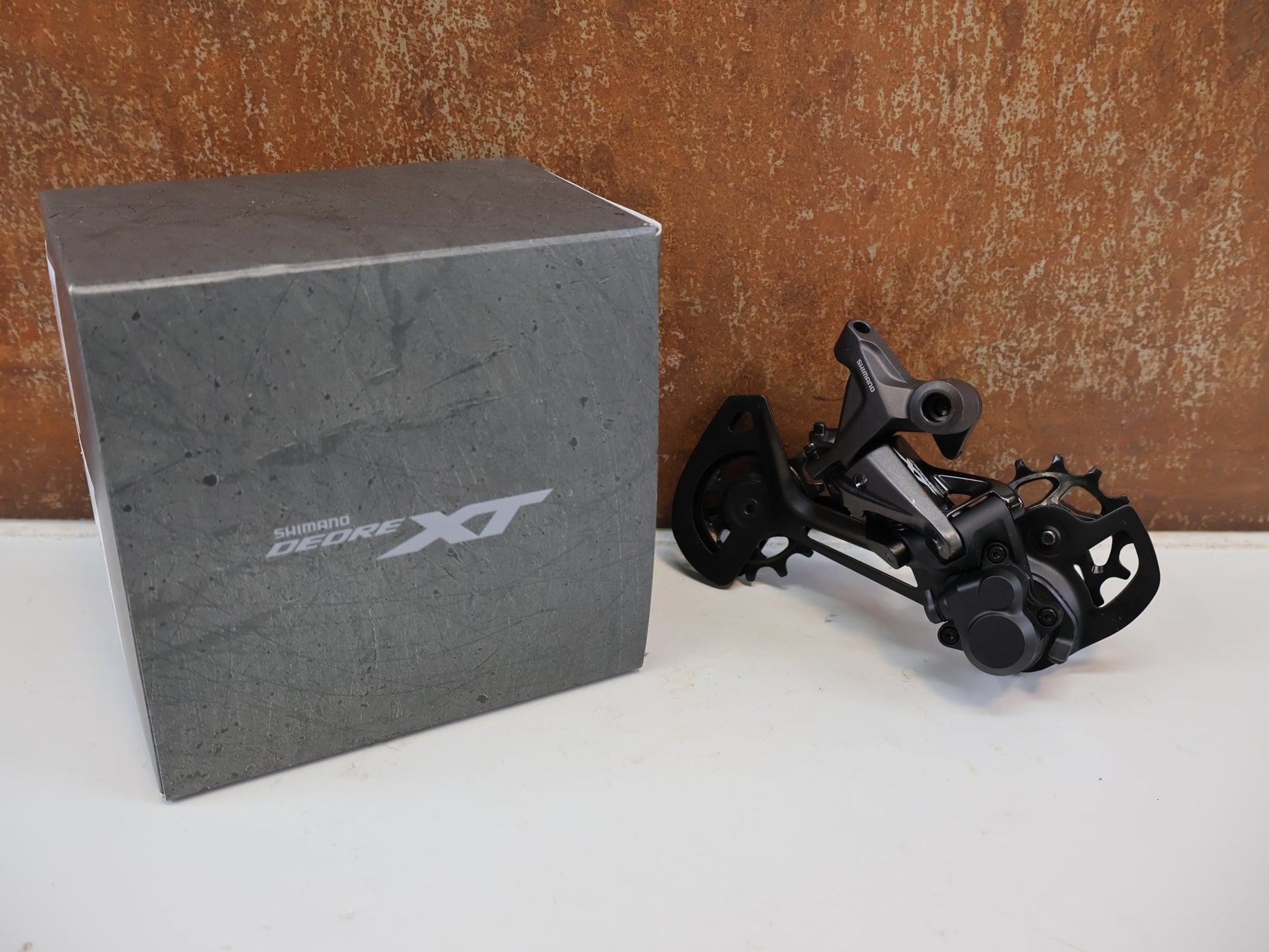 Schaltungsteile von Shimano, SHIMANO DEORE XT RD-M8120 / SCHALTWERK / 2X12-FACH / LONG CAGE vor USEDBIKES-OB.DE Hintergrund