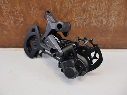 Schaltungsteile von Shimano, SHIMANO DEORE XT RD-M8120 / SCHALTWERK / 2X12-FACH / LONG CAGE vor USEDBIKES-OB.DE Hintergrund