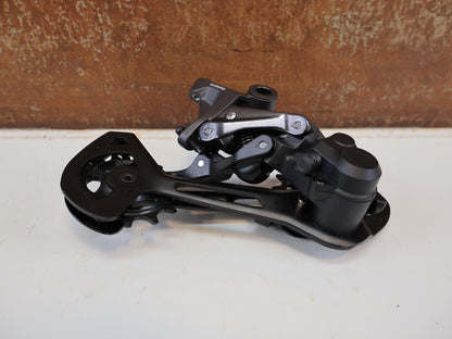 Schaltungsteile von Shimano, SHIMANO DEORE XT RD-M8120 / SCHALTWERK / 2X12-FACH / LONG CAGE vor USEDBIKES-OB.DE Hintergrund