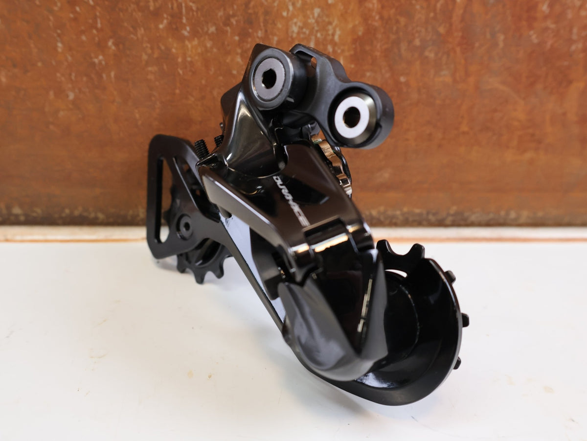 Schaltungsteile von Shimano, Shimano Dura-Ace Di2 RD-R9250 12-fach Schaltwerk Carbon vor USEDBIKES-OB.DE Hintergrund
