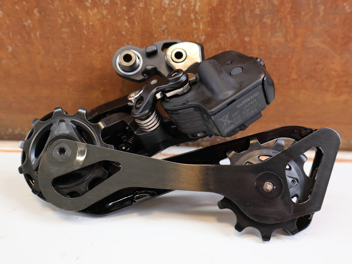 Schaltungsteile von Shimano, Shimano Dura-Ace Di2 RD-R9250 12-fach Schaltwerk Carbon vor USEDBIKES-OB.DE Hintergrund