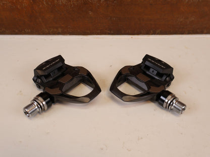 Pedale von Shimano, SHIMANO DURA ACE PD R9100 CARBON SPD SL PEDALE RENNRAD vor USEDBIKES-OB.DE Hintergrund