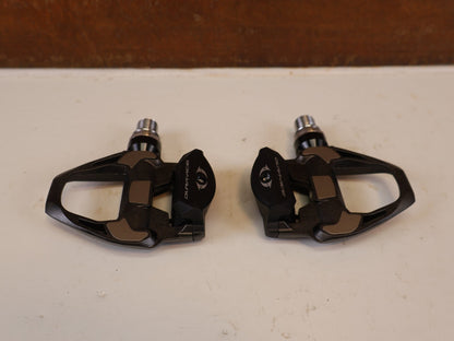 Pedale von Shimano, SHIMANO DURA ACE PD R9100 CARBON SPD SL PEDALE RENNRAD vor USEDBIKES-OB.DE Hintergrund