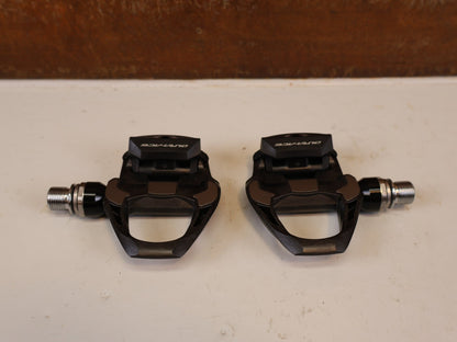 Pedale von Shimano, SHIMANO DURA ACE PD R9100 CARBON SPD SL PEDALE RENNRAD vor USEDBIKES-OB.DE Hintergrund