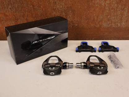 Pedale von Shimano, SHIMANO DURA ACE PD R9100 CARBON SPD SL PEDALE RENNRAD vor USEDBIKES-OB.DE Hintergrund