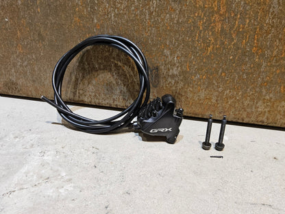 Bremse von Shimano, SHIMANO GRX BREMSSATTEL BR - RX810 - F / - R FLATMOUNT VORNE / HINTEN INKL. LEITUNG in variant_title vor USEDBIKES - OB.DE Hintergrund