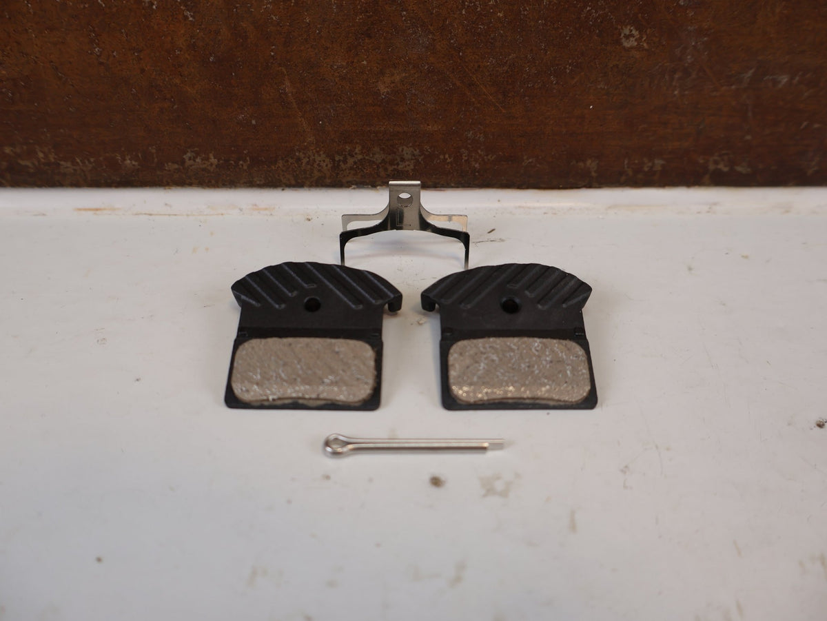 Bremsbelag von Shimano, Shimano J05A Resin Bremsbeläge XTR XT EBPJ05ARFA vor USEDBIKES-OB.DE Hintergrund