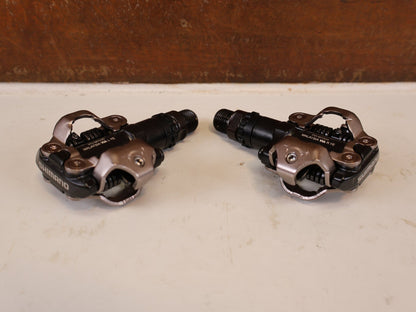 Pedale von Shimano, SHIMANO PD MT520 BEIDSEITIGE SPD KLICKPEDALE SCHWARZ vor USEDBIKES-OB.DE Hintergrund