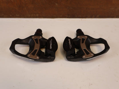 Pedale von Shimano, SHIMANO PD R550 COMPOSITE SPD SL RENNRAD PEDALE vor USEDBIKES-OB.DE Hintergrund