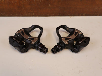 Pedale von Shimano, SHIMANO PD R550 COMPOSITE SPD SL RENNRAD PEDALE vor USEDBIKES-OB.DE Hintergrund