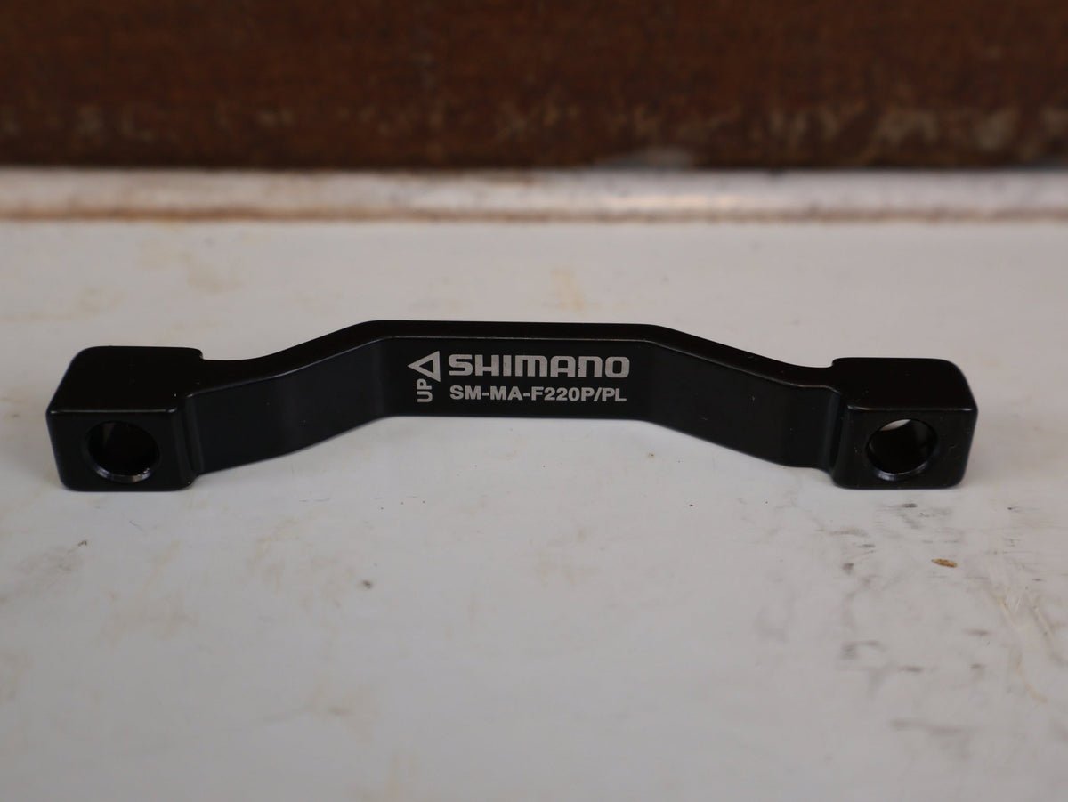 Zubehör von Shimano, SHIMANO POSTMOUNT ADAPTER PM 203 AUF 220 MM SM-MA-F220P/PL vor USEDBIKES-OB.DE Hintergrund