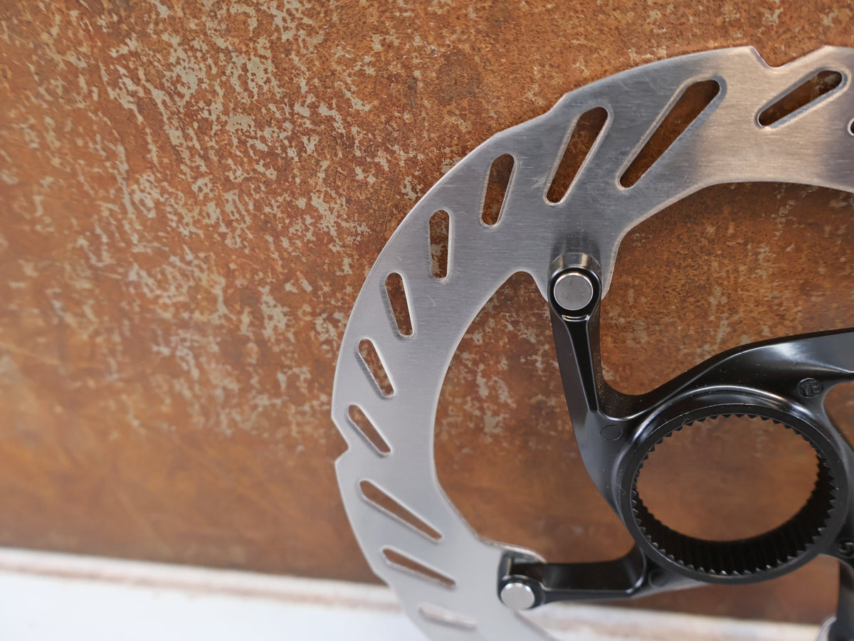 Bremsscheibe von Shimano, Shimano RT-CL700 Center Lock Bremsscheibe 160 mm Innenverzahnung vor USEDBIKES-OB.DE Hintergrund