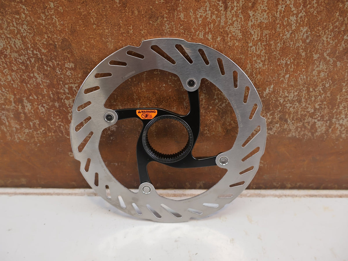 Bremsscheibe von Shimano, Shimano RT-CL700 Center Lock Bremsscheibe 160 mm Innenverzahnung vor USEDBIKES-OB.DE Hintergrund