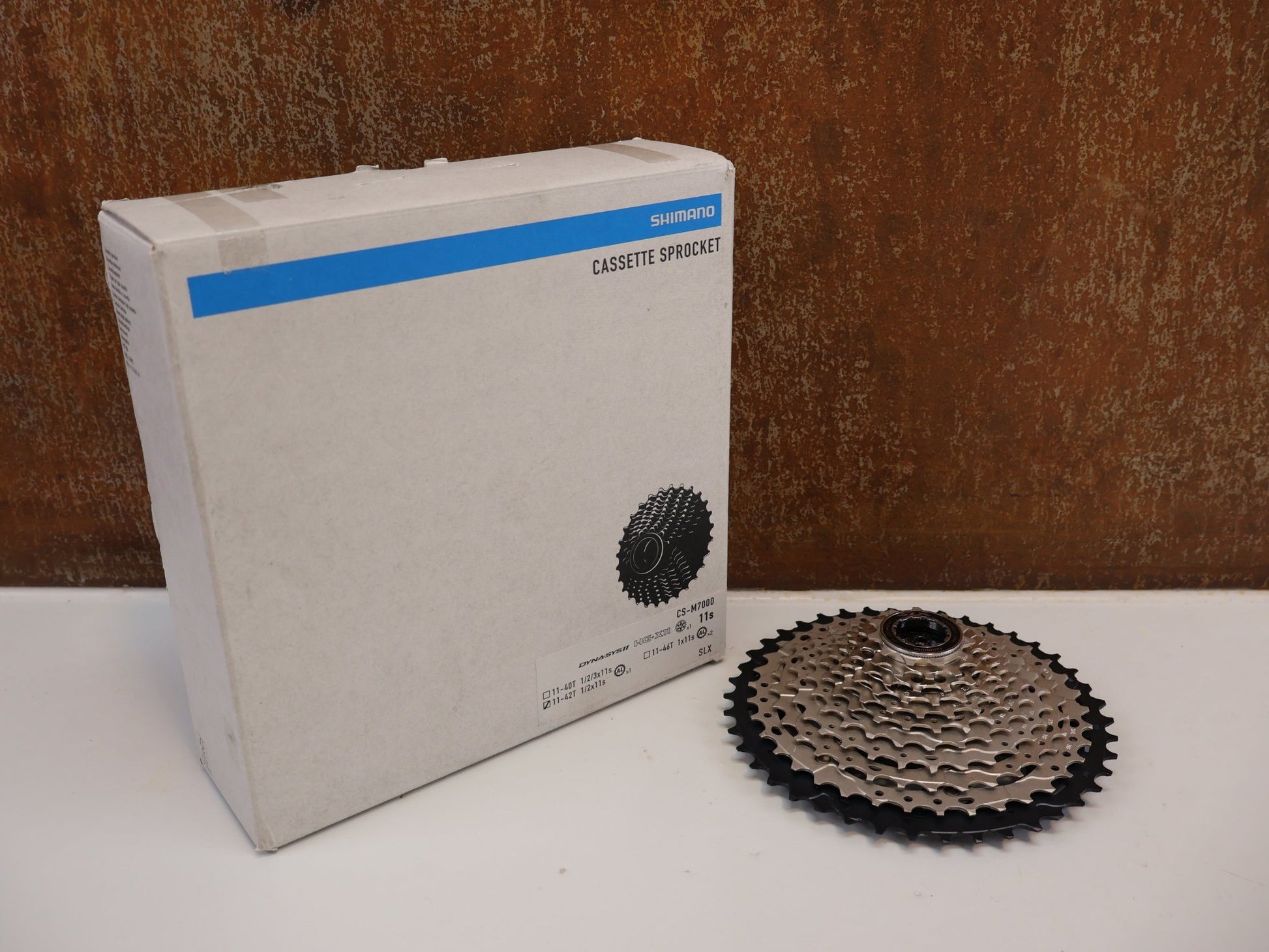 Kassette & Zahnkränze von Shimano, SHIMANO SLX CS - M7000 KASSETTE / 11 - FACH / 11 - 42 ZÄHNE / MTB vor USEDBIKES - OB.DE Hintergrund