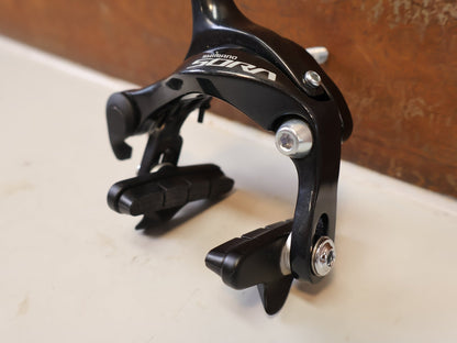 Bremse von Shimano, SHIMANO SORA BR R3000 BREMSE MIT 105 CARTRIDGE BREMSSCHUHEN vor USEDBIKES-OB.DE Hintergrund