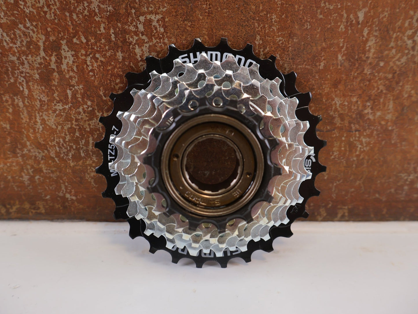 Kassette & Zahnkränze von Shimano, SHIMANO TOURNEY MF - TZ510 FREILAUFZAHNKRANZ / 7 - FACH / 14 - 28Z / SCHRAUBKRANZ / EMFTZ5107428 vor USEDBIKES - OB.DE Hintergrund