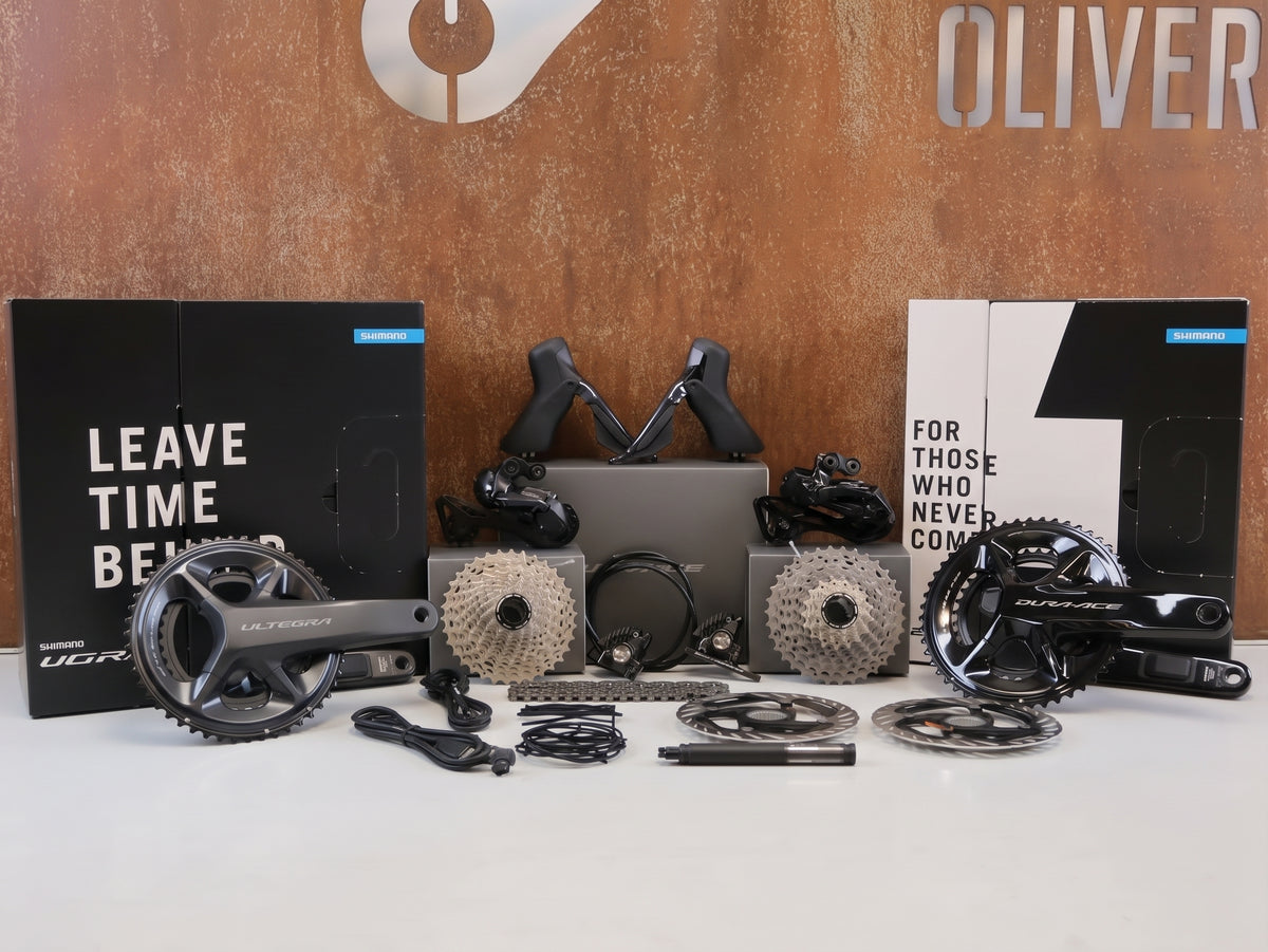 Zwei komplette elektronische Shimano Di2 Schaltgruppen im direkten Vergleich: Links die Ultegra R8100 und rechts die Dura-Ace R9200, jeweils inklusive Powermeter-Kurbel und Zubehör.