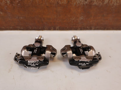 Pedale von Shimano, Shimano XTR PD-M9000 SPD MTB Pedale Klickpedale 308g Set vor USEDBIKES-OB.DE Hintergrund