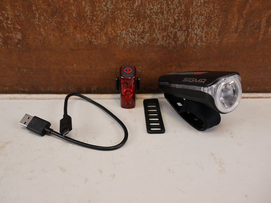 Beleuchtung von Sigma, SIGMA AURA 60 INFINITY SET USB AKKU BELEUCHTUNG STVZO vor USEDBIKES-OB.DE Hintergrund