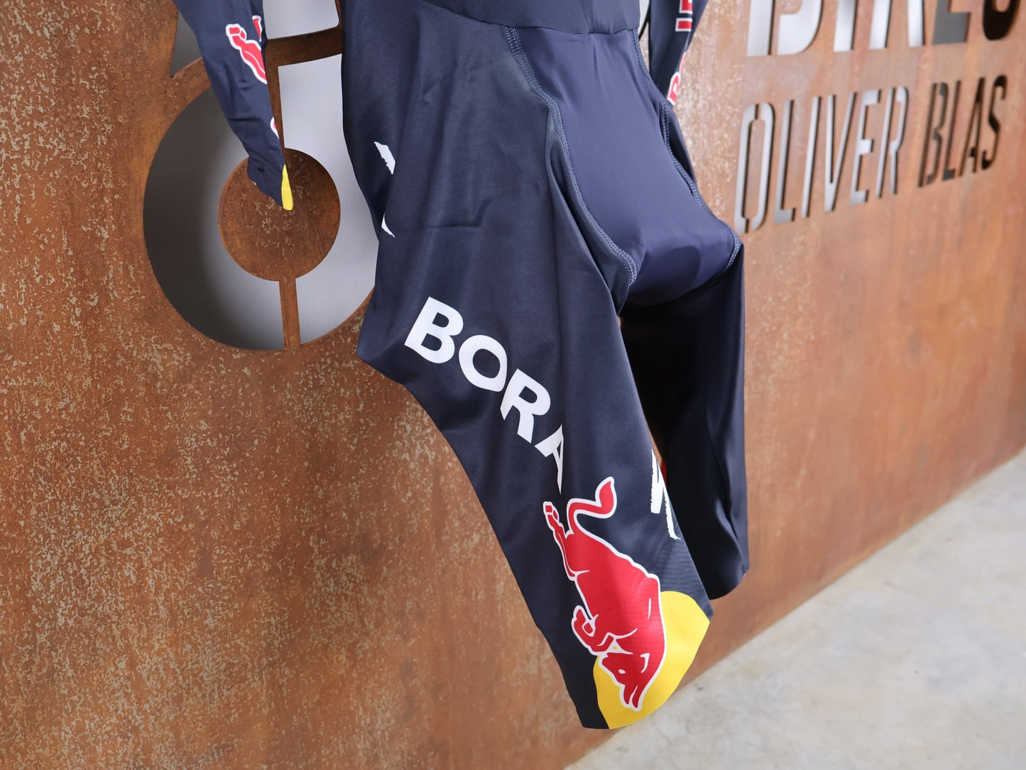 Anzug - BOH von Specialized, SPECIALIZED RED BULL - BORA HANSGROHE AERO SKIN SUIT LS / LANGARM EINTEILER U23 vor USEDBIKES - OB.DE Hintergrund