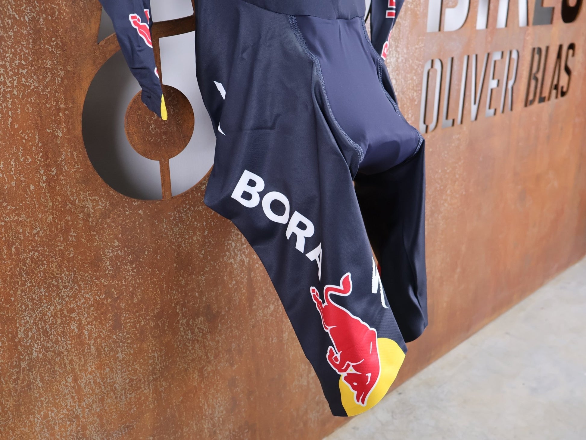 Anzug - BOH von Specialized, SPECIALIZED RED BULL - BORA HANSGROHE AERO SKIN SUIT LS / LANGARM EINTEILER U23 vor USEDBIKES - OB.DE Hintergrund