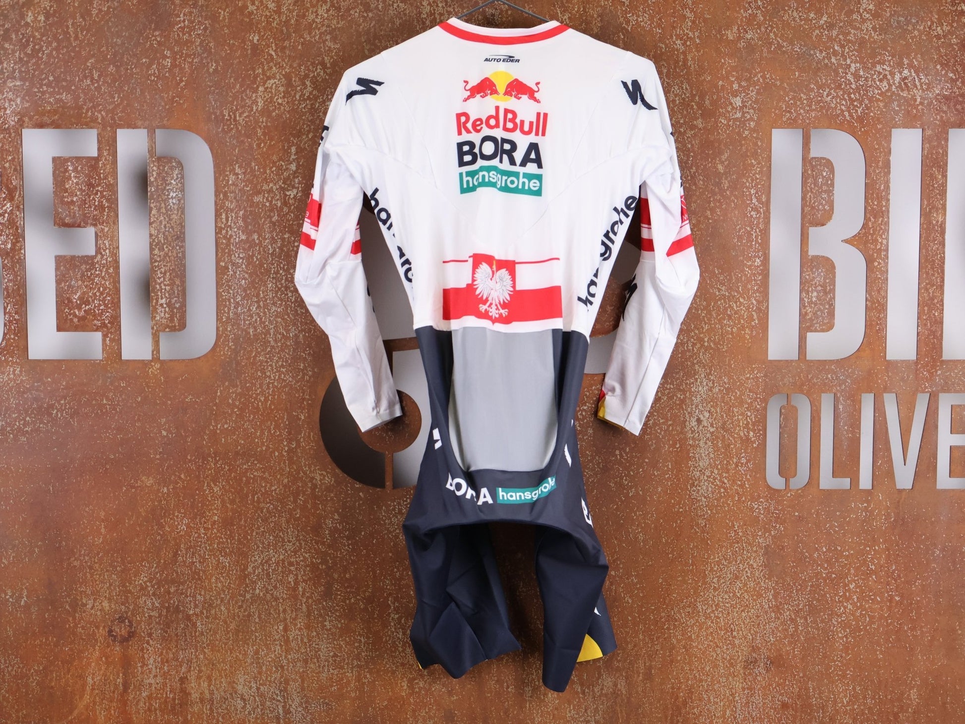 Anzug - BOH von Specialized, SPECIALIZED RED BULL - BORA HANSGROHE AERO SKIN SUIT LS / POLAND CHAMPION vor USEDBIKES - OB.DE Hintergrund